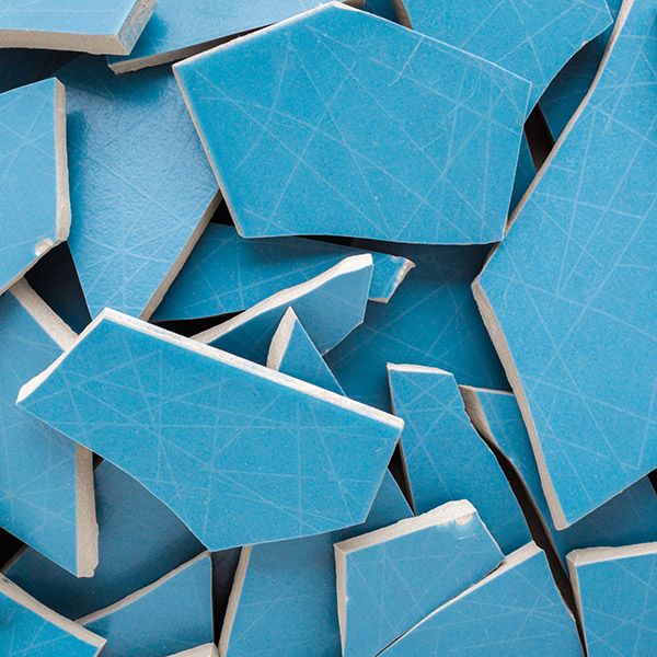Heap of cracked blue ceramic wall or floor tiles background. Closeup. Top down view.